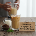 Segelas es kopi gula aren dengan lapisan susu dan es batu di meja kayu, disajikan dengan gula aren alami di sampingnya.